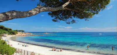 a beach with people on the sand and the ocean at Camping Porto Vecchio in Porto-Vecchio