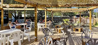 a patio with white chairs and people sitting at tables at Camping Porto Vecchio in Porto-Vecchio