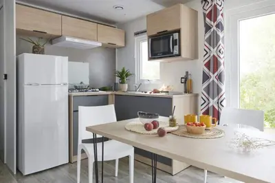 a kitchen with a table and a white refrigerator at Camping Porto Vecchio in Porto-Vecchio