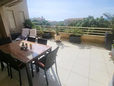 a patio with a wooden table and chairs on a balcony at Christelle in Propriano