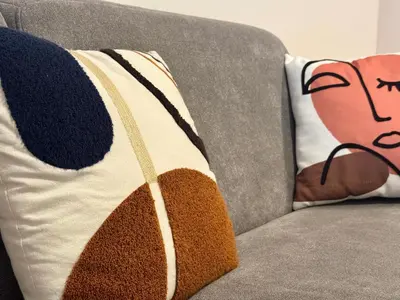 a pillow sitting on a couch with a blanket at Rena Bianca tout confort proche plage et centre ville in Propriano