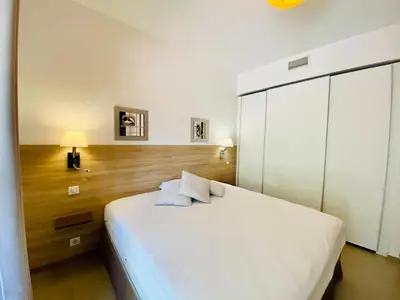 a bedroom with a large white bed and a cabinet at Rena Bianca tout confort proche plage et centre ville in Propriano