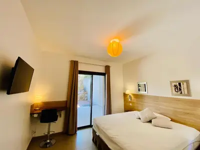a bedroom with a bed and a tv and a window at Rena Bianca tout confort proche plage et centre ville in Propriano