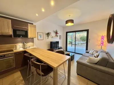a kitchen and living room with a table and a couch at Rena Bianca tout confort proche plage et centre ville in Propriano