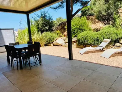 a patio with a table and chairs on it at Rena Bianca tout confort proche plage et centre ville in Propriano