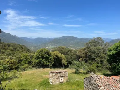 an old stone building in a field with mountains in the background at Tradition Corse & Modernité Ì Caseddi dì Barabè Appartement A Cantina in Granace
