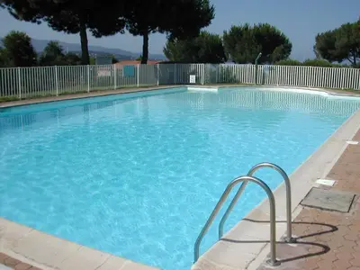 a large swimming pool with blue water at Studio vue mer à Porticcio proche aéroport Ajaccio in Porticcio