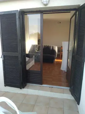a living room with sliding glass doors and a couch at Studio vue mer à Porticcio proche aéroport Ajaccio in Porticcio