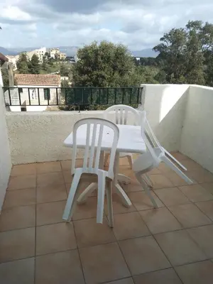 two white chairs and a table on a balcony at Studio vue mer à Porticcio proche aéroport Ajaccio in Porticcio
