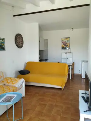 a living room with a yellow couch and a table at Studio vue mer à Porticcio proche aéroport Ajaccio in Porticcio