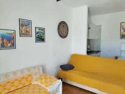 a living room with a yellow couch and a chair at Studio vue mer à Porticcio proche aéroport Ajaccio in Porticcio