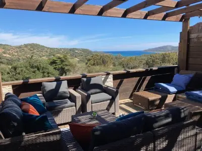 a deck with chairs and a couch and a view of the ocean at Appartement Cemiliana in Bonifacio