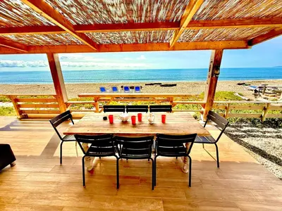 a wooden table with chairs and the beach at Casamarina2a Maisons bord de mer in Ghisonaccia