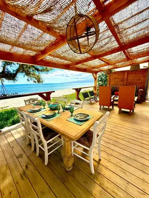 a wooden table and chairs on a deck with the beach at Casamarina2a Maisons bord de mer in Ghisonaccia