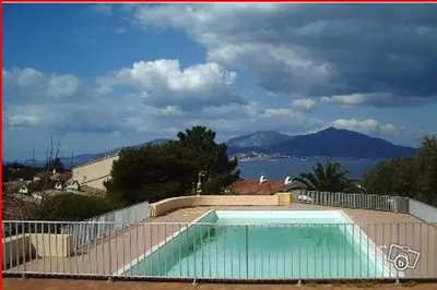 a swimming pool in front of a fence with a mountain at T2 vue mer à Porticcio, proche aéroport Ajaccio in Porticcio