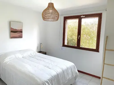 a white bedroom with a bed and a window at Villa privée dans un cadre verdoyant , piscine et grand jardin in Porto-Vecchio
