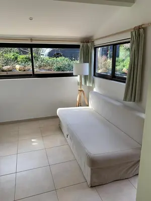 a living room with a couch and two windows at Villa privée dans un cadre verdoyant , piscine et grand jardin in Porto-Vecchio