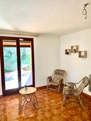 a living room with two chairs and a table at Villa privée dans un cadre verdoyant , piscine et grand jardin in Porto-Vecchio