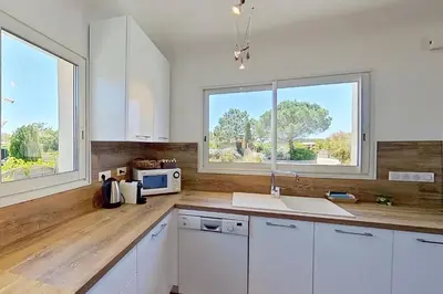 a kitchen with white cabinets and a counter top at CALA CORSICA - Villas 5 Etoiles T5 Piscine privée - Villa T4 Piscine privée chauffée - Villa T3 Piscine partagée - Internet Fibre - Entièrement Climatisée à Lecci de Porto-Vecchio Cala Rossa in Lecci