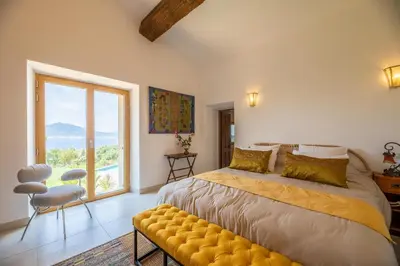 a bedroom with a large bed and a large window at Domain U Tempu Persu Sleeps 12 with Park in Porticcio