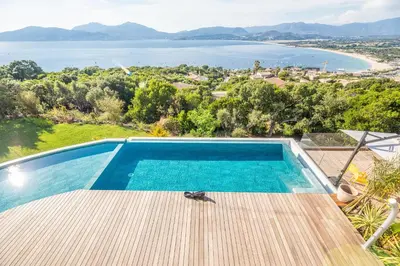 a bird sitting on a deck next to a swimming pool at Domain U Tempu Persu Sleeps 12 with Park in Porticcio