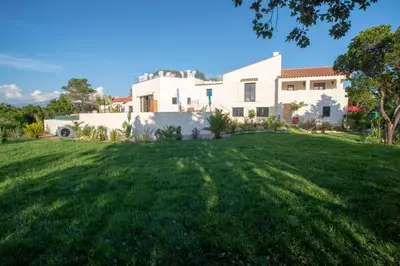 a white house with a large grass yard at Domain U Tempu Persu Sleeps 12 with Park in Porticcio
