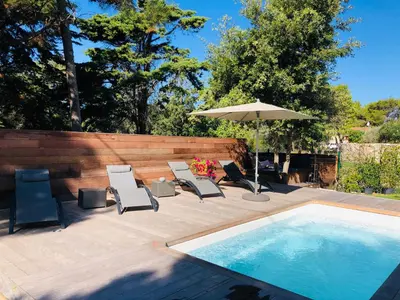 a patio with chairs and an umbrella and a pool at A MUREDDA in Bonifacio