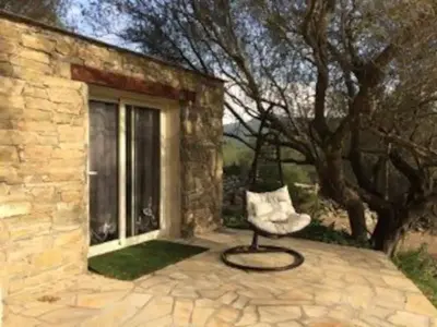 a chair sitting on a patio next to a window at Petite maison en pierre in Saint-Florent