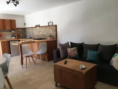 a living room with a black couch and a kitchen at Petite maison en pierre in Saint-Florent