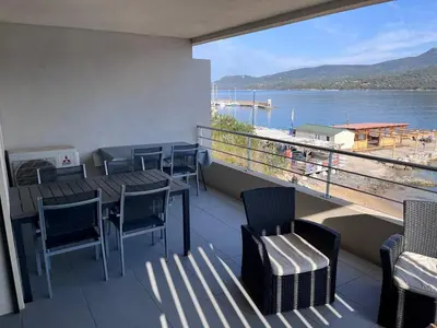 a balcony with tables and chairs and a view of the water at Appartement les pieds dans l'eau 3 Chambres - Propriano - Corse in Propriano