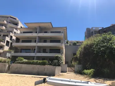 a white apartment building in front of a beach at Appartement les pieds dans l'eau 3 Chambres - Propriano - Corse in Propriano