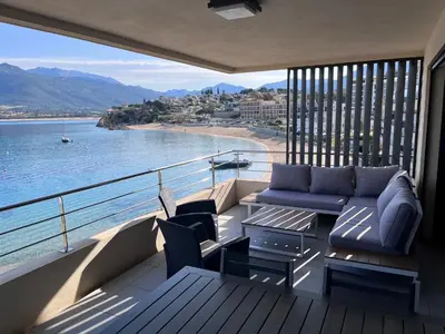 a balcony with a couch and a view of a beach at Appartement les pieds dans l'eau 3 Chambres - Propriano - Corse in Propriano