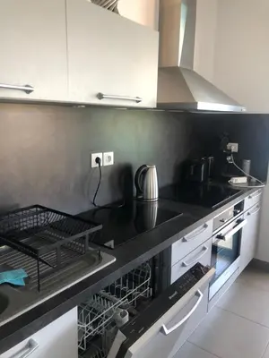 a kitchen with black counters and white cabinets at Appartement les pieds dans l'eau 3 Chambres - Propriano - Corse in Propriano