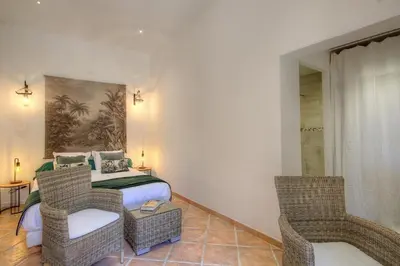 a bedroom with a bed and two wicker chairs at Le Campu Latinu in Lama