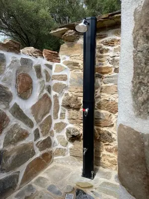 a black pole on the side of a stone wall at Bergerie tout confort L'immortelle in Saint-Florent