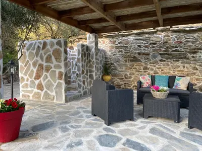 a patio with chairs and a stone wall at Bergerie tout confort L'immortelle in Saint-Florent