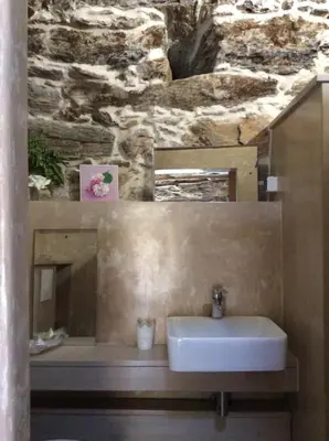 a bathroom with a sink and a stone wall at Bergerie tout confort L'immortelle in Saint-Florent