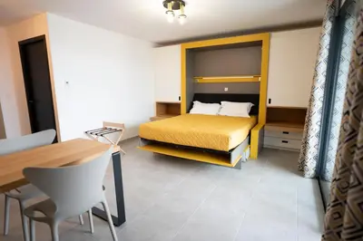 a bedroom with a bed and a desk and a table at hôtel résidence a torra in Vescovato
