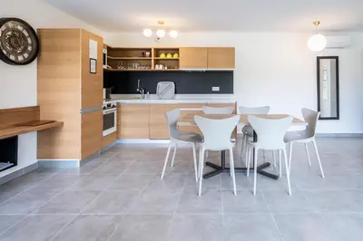 a kitchen with a table and some white chairs at hôtel résidence a torra in Vescovato