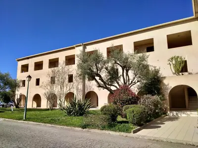 a building with trees and bushes in front of it at studio à 100m de la plage et de la piscine in Cervione