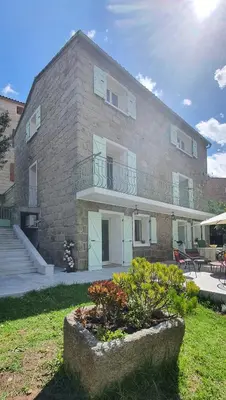 a large brick building with a balcony and a yard at Charmant appartement en Rez de jardin in Sartène