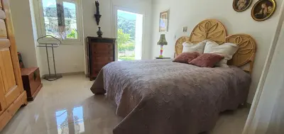 a bedroom with a large bed with a wooden headboard at Charmant appartement en Rez de jardin in Sartène
