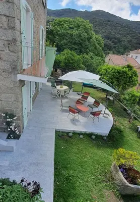 a patio with chairs and a table and umbrella at Charmant appartement en Rez de jardin in Sartène