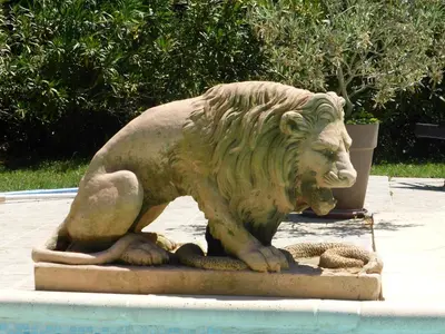 a statue of a lion sitting next to a pool at Relais de Bravone in Linguizzetta