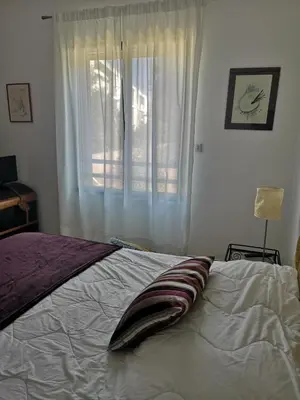 a bedroom with a white bed with a window at T3 vue mer à Propriano in Propriano