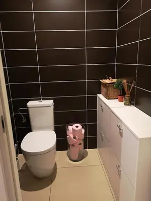 a bathroom with a toilet and a black tiled wall at T3 vue mer à Propriano in Propriano