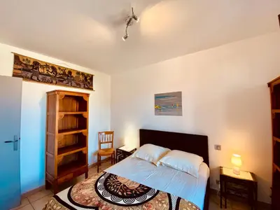 a bedroom with a bed and a book shelf at Joli deux pièces, centre ville et proche plage in Propriano