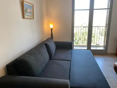 a blue couch in a living room with a lamp at Joli deux pièces, centre ville et proche plage in Propriano