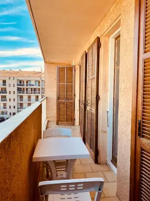 a balcony with a table and chairs on a building at Joli deux pièces, centre ville et proche plage in Propriano