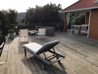 a chair on a deck with a table and chairs at VILLA GIOIA -Vue mer- proche plage de Favone in Conca